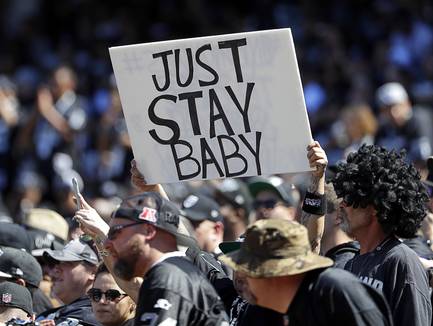 A Oakland Raiders fan holds up a sign about the team possibly moving during the first half of an NFL football game between the Oakland Raiders and the Atlanta Falcons in Oakland, Calif., Sunday, Sept. 18, 2016.
