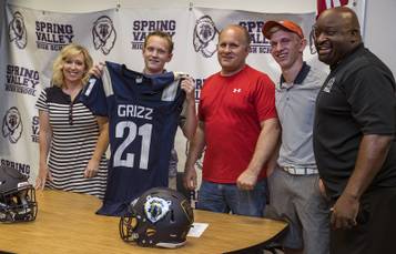Prospective player Blake Johnson holds up a jersey joined by his family and Spring Valley High football head coach Marcus Teal as the program hosts a signing day event for incoming freshmen with hopes of drumming up interest to play on Tuesday, May 30, 2017.