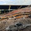 Photo: A car sits crushed, engulfed in a pile of rubble f Photo: A car sits crushed, engulfed in a pile of rubble f