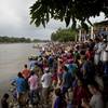 Photo: Hundreds of Honduran migrants stand at the shore o Photo: Hundreds of Honduran migrants stand at the shore o