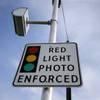 Photo: A red light photo enforcement sign is seen below a Photo: A red light photo enforcement sign is seen below a